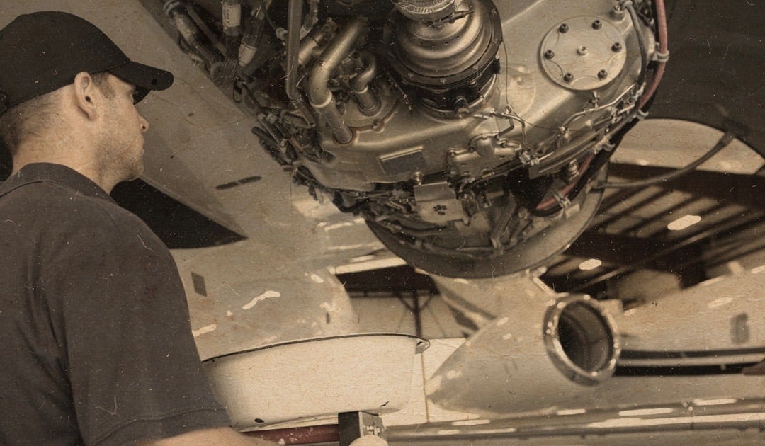 Aircraft technician looking at a jet engine with a sepia filter